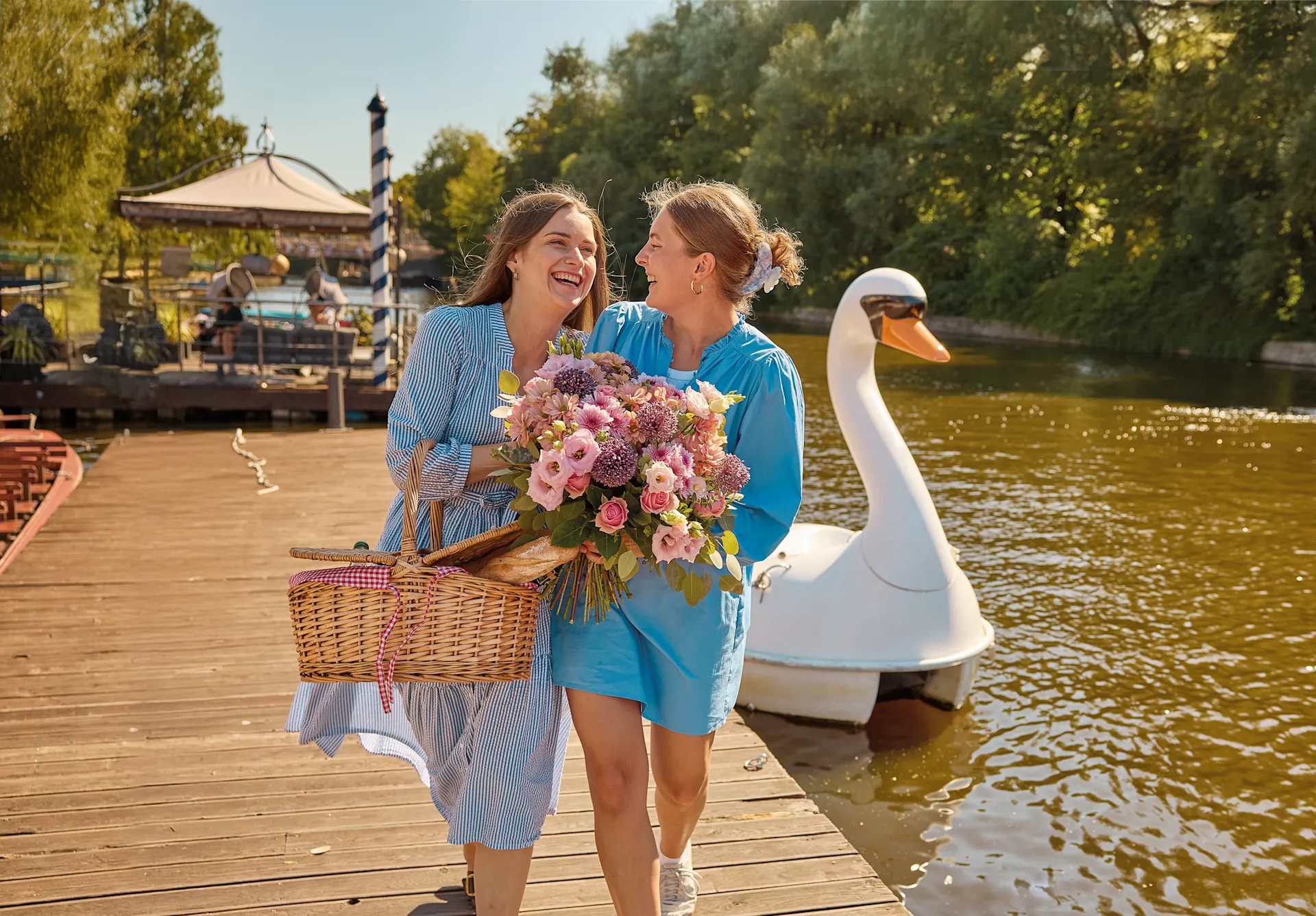 Offizielles BLUME2000-Lifestylebild mit zwei Empfängerinnen und einem sommerlichen Blumenstrauß am See